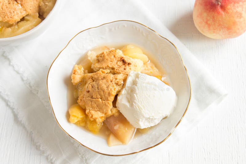 Homemade peach cobbler with vanilla ice cream over rustic wooden background - healthy pastry dessert. Homemade peach cobbler with vanilla ice cream over rustic wooden background - healthy pastry dessert