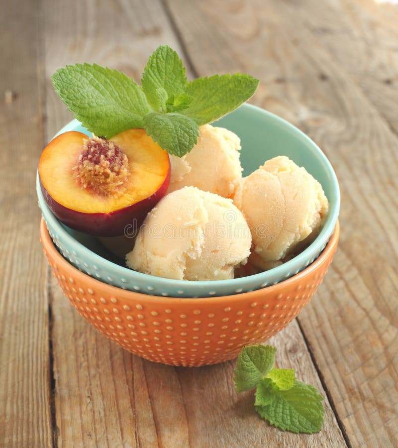 Peach ice cream in bowl on wooden table