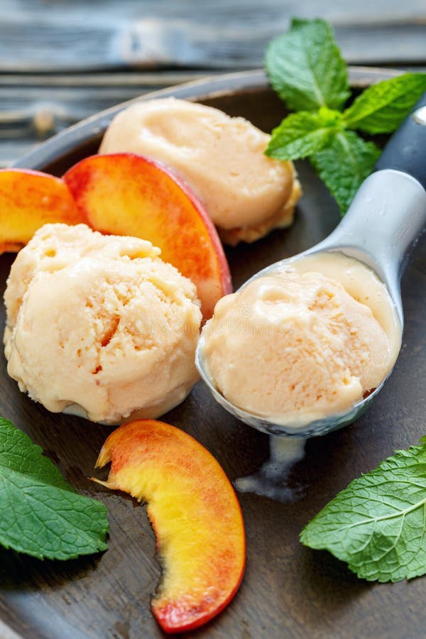 Peach ice cream spoon, peach pieces and mint leaves.