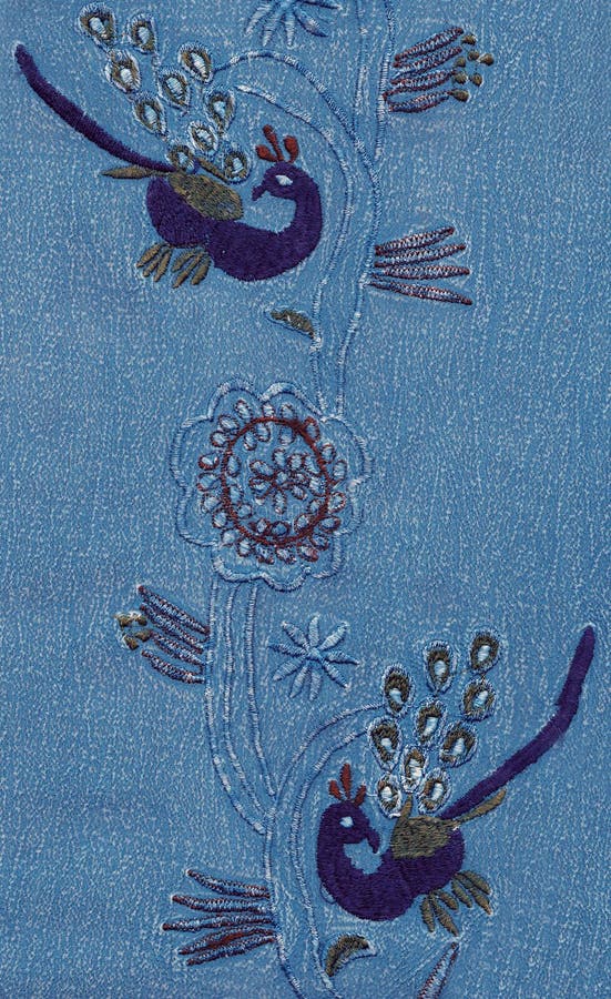 Peacock embroidery on blue cotton. royalty free stock image