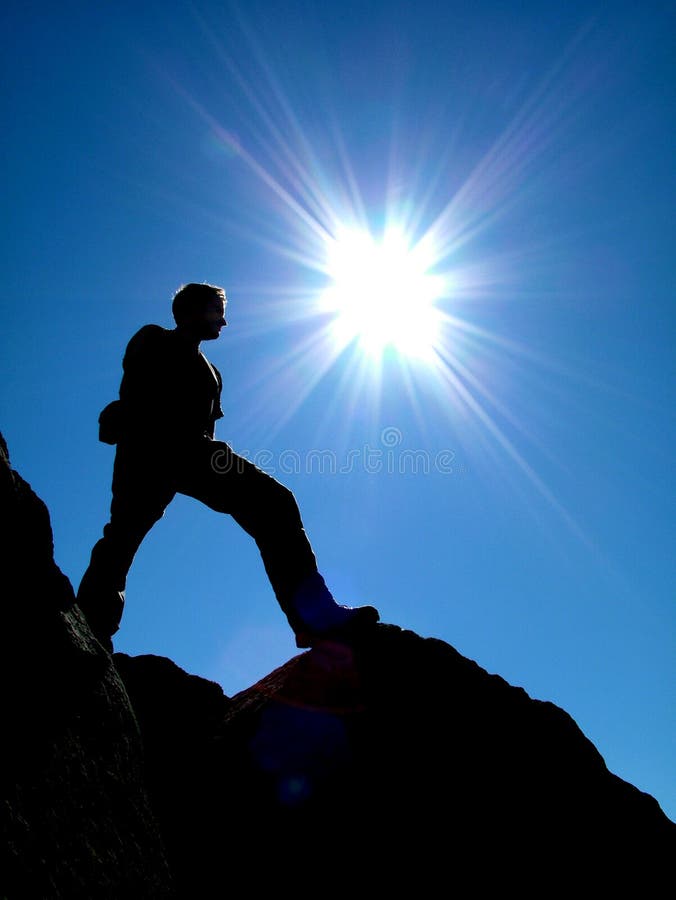Un rock / alpinista al vertice della sua salita, crogiolandosi al sole brillante.