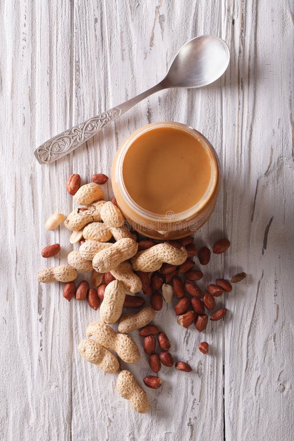 Peanut Butter in a Glass Jar and Nuts Closeup Vertical Top View Stock
