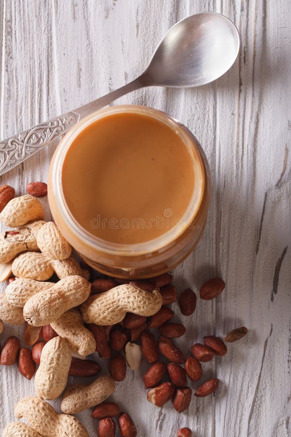 Peanut Butter in a Glass Jar and Nuts Vertical Top View Stock Photo