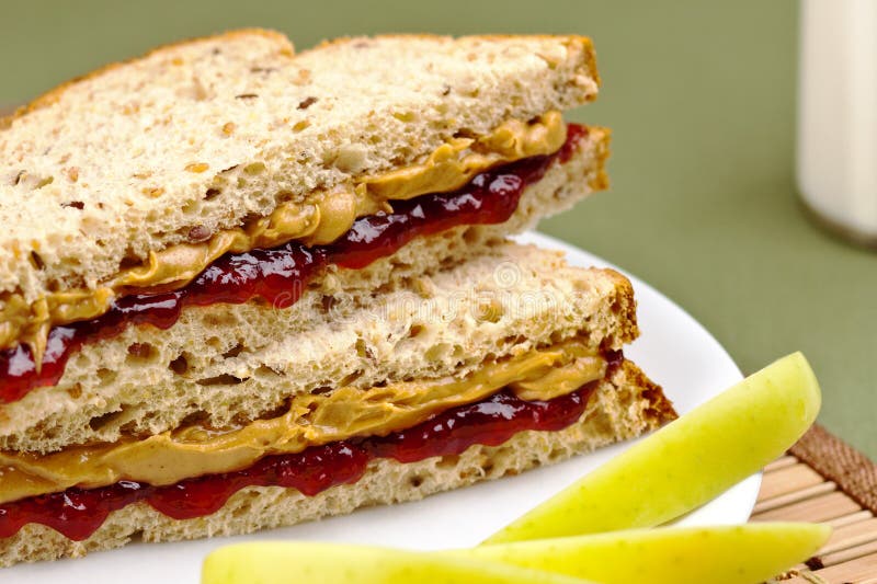 Healthy and delicious childs lunch of peanut butter and jelly sandwich with green apples and milk