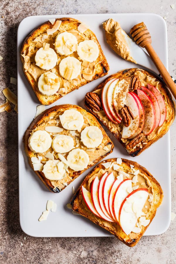 Peanut butter toasts with banana and apple on a gray background, flat lay