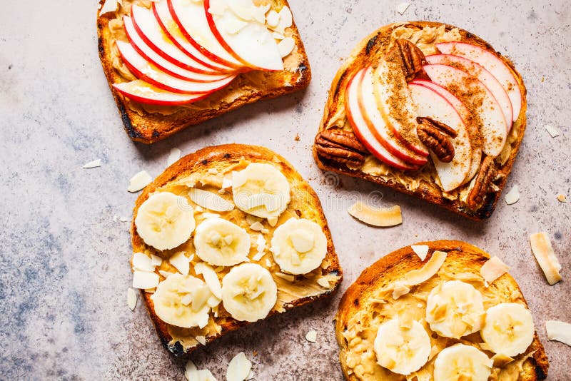 Peanut butter toasts with banana and apple on a gray background