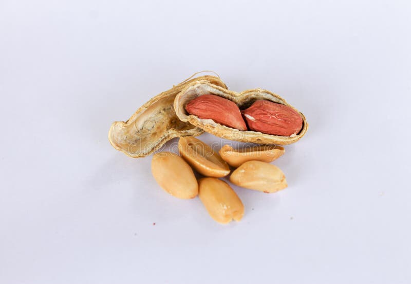 Peanuts piled up separately on a white background. One has been peeled off to reveal a red seed inside. There are two seeds that have been carved apart in front