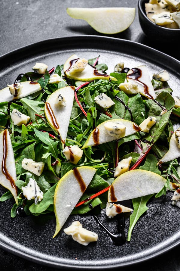 Pear, Blue Cheese, Arugula and Nut Salad on Plate. Black Background