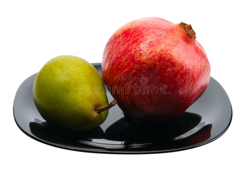 Pomegranate and pear on a black platte, isolated. Pomegranate and pear on a black platte, isolated.