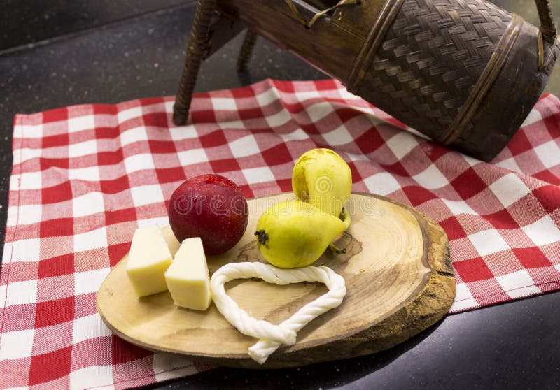 Pear, red plum and cheeses on wooden chopping board.
