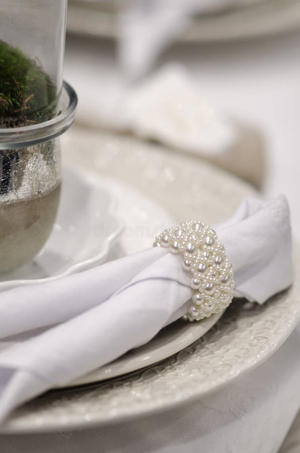 Pearl napkin ring luxury table set. A beautiful and luxurious table set in white with a white pearl napkin ring, festive dining at a wedding party royalty free stock photo Pearl napkin ring luxury table set. A beautiful and luxurious table set in white with a white pearl napkin ring, festive dining at a wedding party royalty free stock photo
