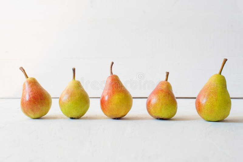 Pears on the light wooden background, Ripe juicy yellow pears stand in a row on a white background. Layout for the