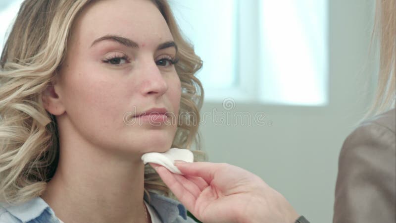 Peau de nettoyage d'artiste de maquillage sur le visage modèle