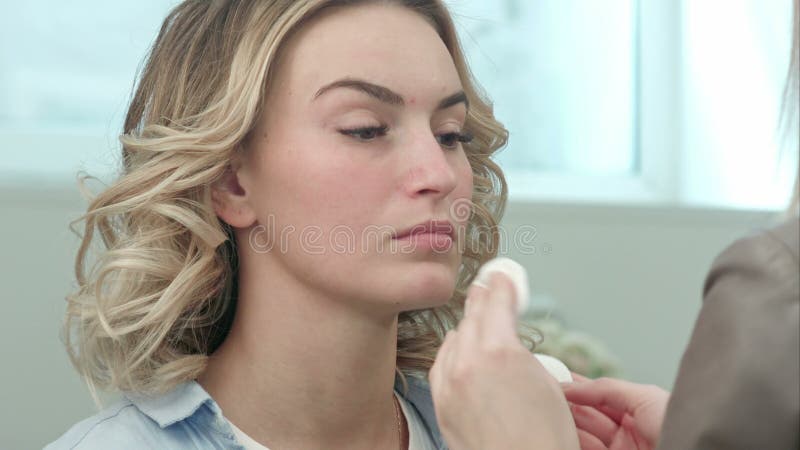 Peau de préparation et de nettoyage d'artiste de maquillage de jeune modèle blond