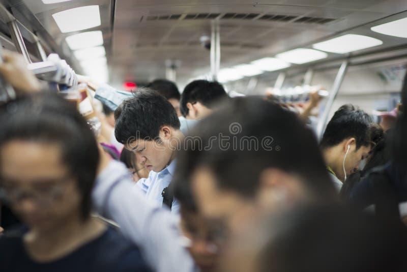 Pechino, Cina - 08 02 2016: Popolo cinese che esamina i loro telefoni cellulari dentro una metropolitana a Pechino, Cina immagini stock Pechino, Cina - 08 02 2016: Popolo cinese che esamina i loro telefoni cellulari dentro una metropolitana a Pechino, Cina immagini stock
