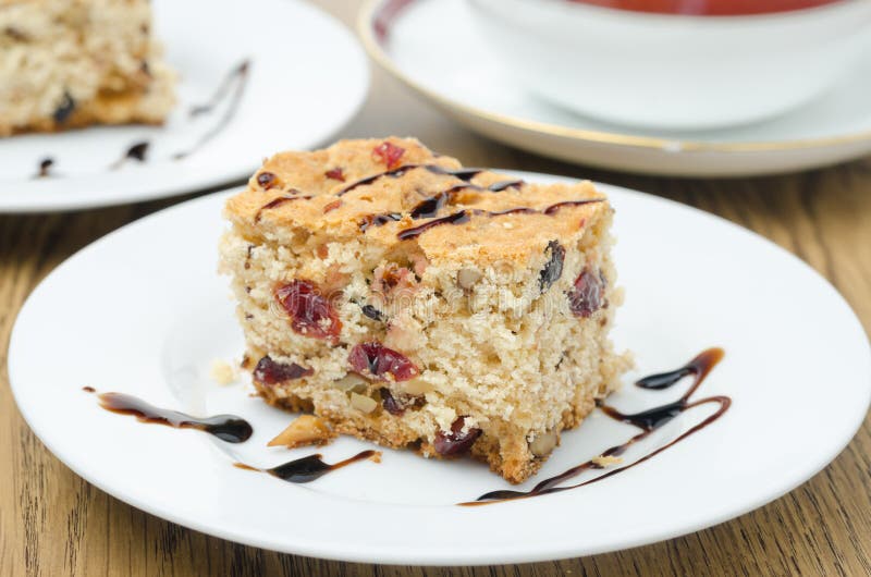 Pedazo de torta con los arándanos secados y las nueces adornados con cho foto de archivo Pedazo de torta con los arándanos secados y las nueces adornados con cho foto de archivo