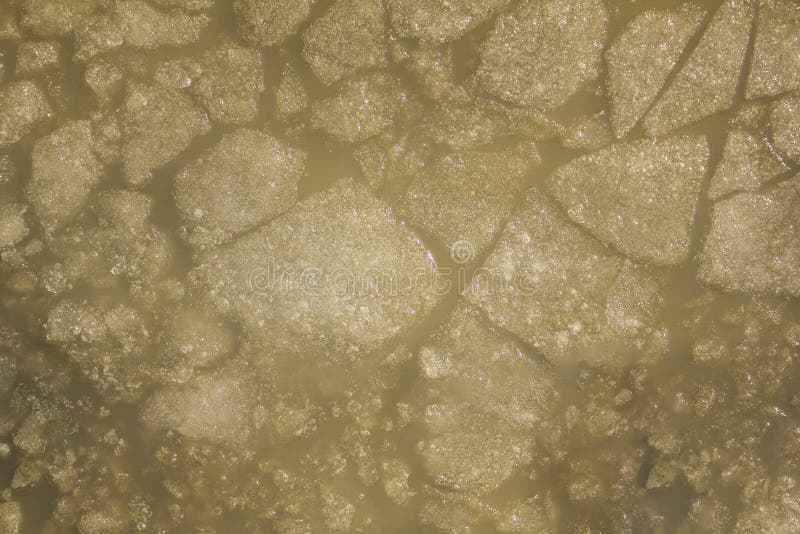 Pedazos grandes de hielo de diversos formas y tamaños en la opinión de top amarilla gris fangosa del agua foto de archivo libre de regalías Pedazos grandes de hielo de diversos formas y tamaños en la opinión de top amarilla gris fangosa del agua foto de archivo libre de regalías