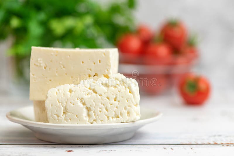 Pedazos grandes de queso feta en los tomates blancos de la placa y de cereza en fondo ligero Foco selectivo, alta llave fotos de archivo libres de regalías Pedazos grandes de queso feta en los tomates blancos de la placa y de cereza en fondo ligero Foco selectivo, alta llave fotos de archivo libres de regalías