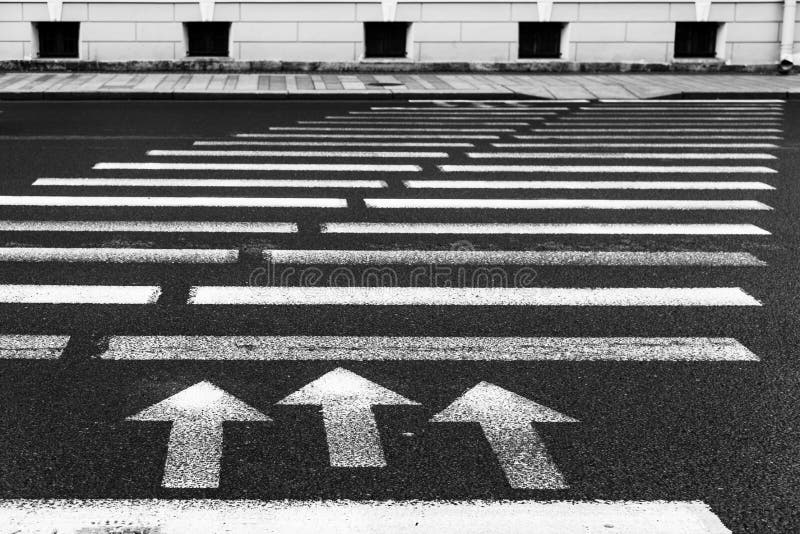 Pedestrian crossing with road marking: white arrows and rectangles on dark asphalt stock photos