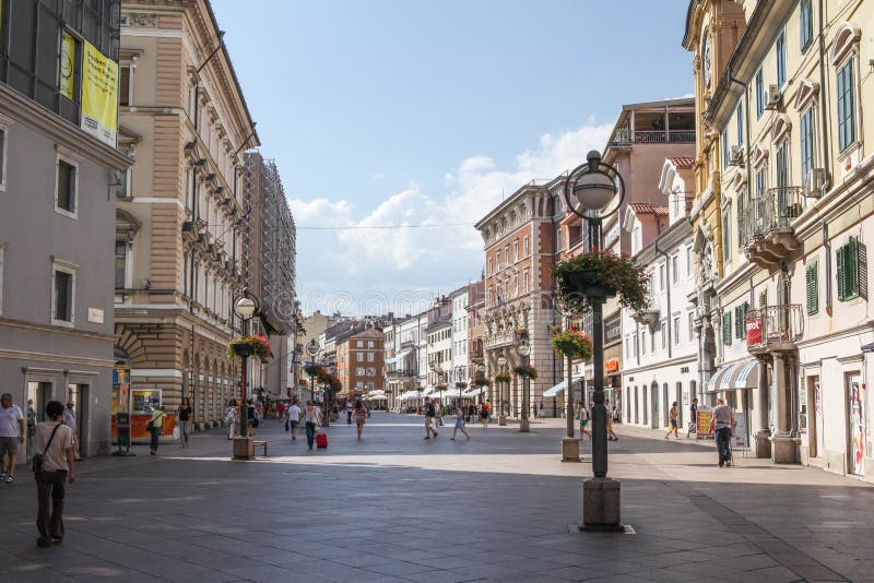 Rijeka, Croatia – August 7, 2012: City center pedestrian zone in Rijeka with surrounding buildings and people walking up and down the street. Rijeka is the center of Primorje-Gorski Kotar County and the third-largest city in Croatia. Rijeka, Croatia – August 7, 2012: City center pedestrian zone in Rijeka with surrounding buildings and people walking up and down the street. Rijeka is the center of Primorje-Gorski Kotar County and the third-largest city in Croatia.