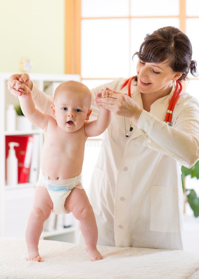 Pediater die leuke babyjongen onderzoeken en zijn het lopen reflex testen