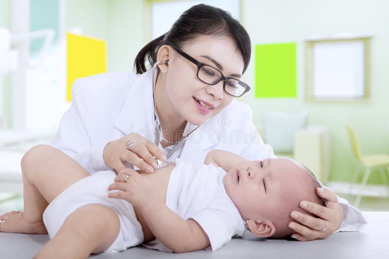 Pediatra che esamina un piccolo bambino immagine stock libera da diritti Pediatra che esamina un piccolo bambino immagine stock libera da diritti