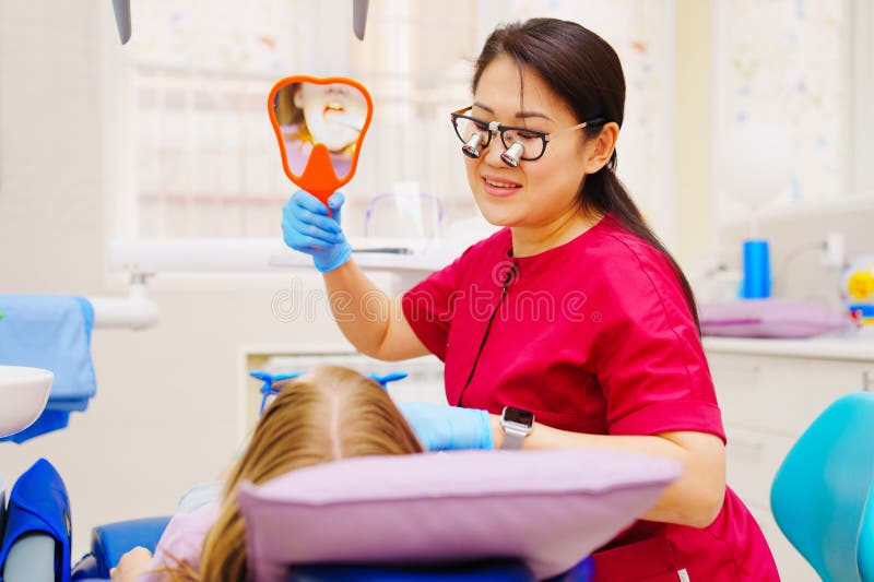 The Pediatric Dentist Shows the Patient Teeth in the Reflection of the Mirror. Stock Photo
