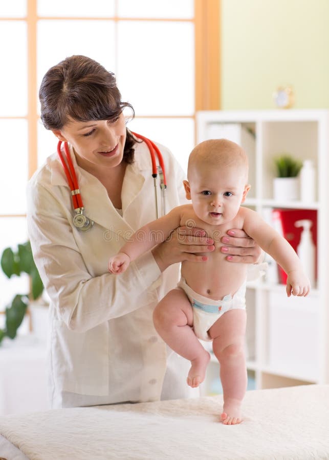 Pediatrician examining cute baby boy. Doctor testing walking reflex