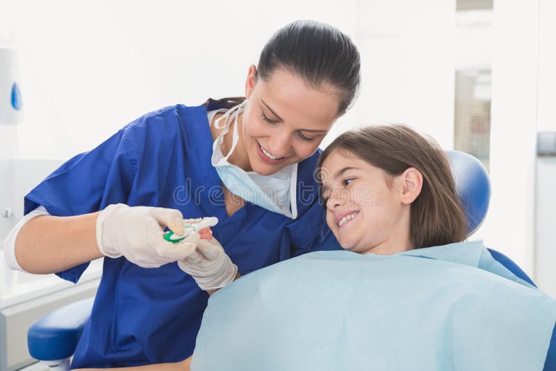 Pediatrische tandarts die aan jonge patiënt verklaren hoe gebruikstandenborstel