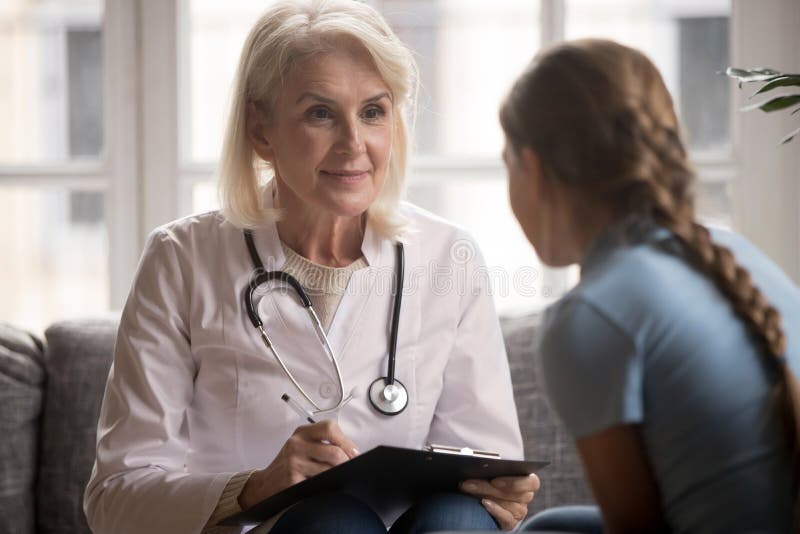 Pediatru de vârstă mijlocie, care ascultă plângerile tinerilor pacienți. stock images