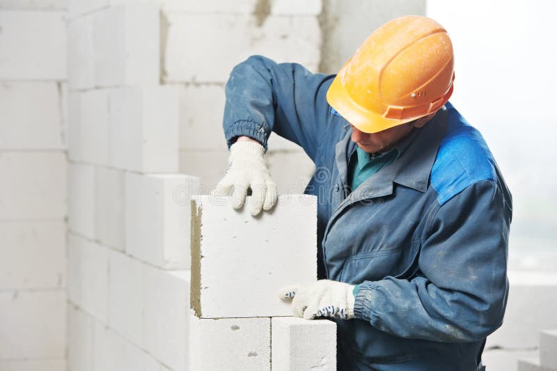 Construction mason worker bricklayer installing calcium silicate brick during indoor wall creation. Construction mason worker bricklayer installing calcium silicate brick during indoor wall creation