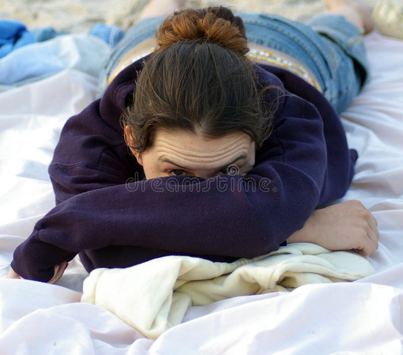 A teenage girl peeks her head out from her folded arms. A teenage girl peeks her head out from her folded arms