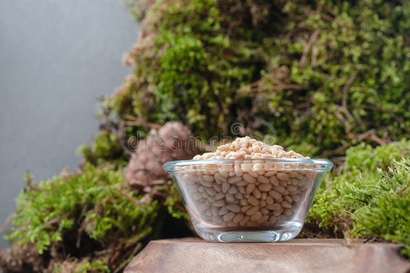Peeled pine nuts in a glass bowl on a natural background royalty free stock photo