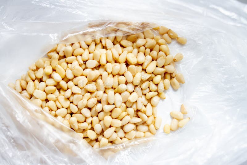 Peeled pine nuts in a plastic bag on a white background stock photography