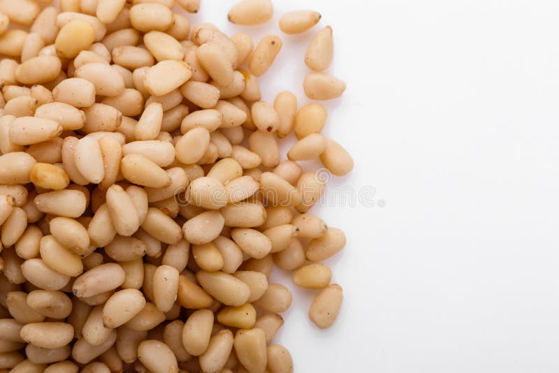 Peeled pine nuts on a white acrylic background royalty free stock photo