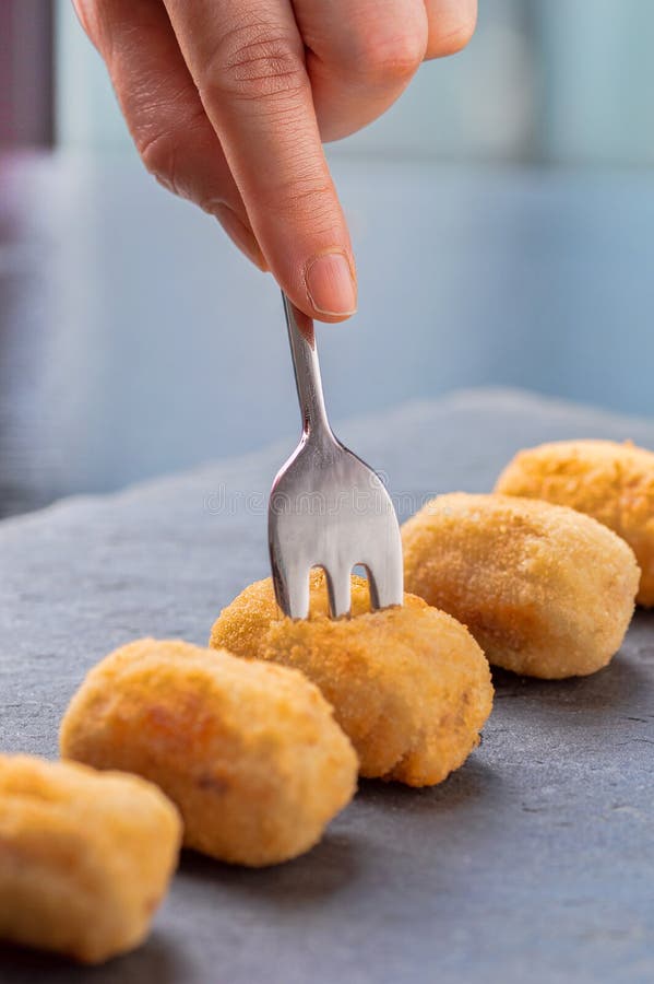 Croquete caseiro tradicional espanhol no garfo com fundo escuro