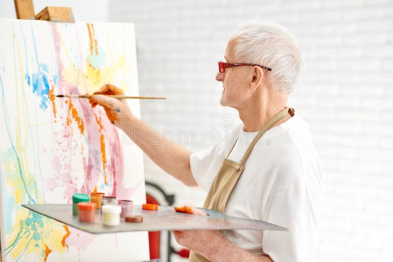Peintre doué supérieur tout en peignant son chef d'oeuvre au studio photo stock Peintre doué supérieur tout en peignant son chef d'oeuvre au studio photo stock