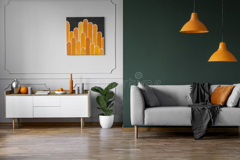 Peinture orange abstraite sur le mur gris du salon élégant intérieur avec les meubles en bois blancs et le divan gris Peinture orange abstraite sur le mur gris du salon élégant intérieur avec les meubles en bois blancs et le divan gris