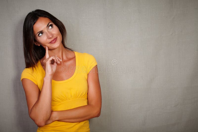 Pensive brunette lady with straight hair thinking while looking away - copy space. Pensive brunette lady with straight hair thinking while looking away - copy space