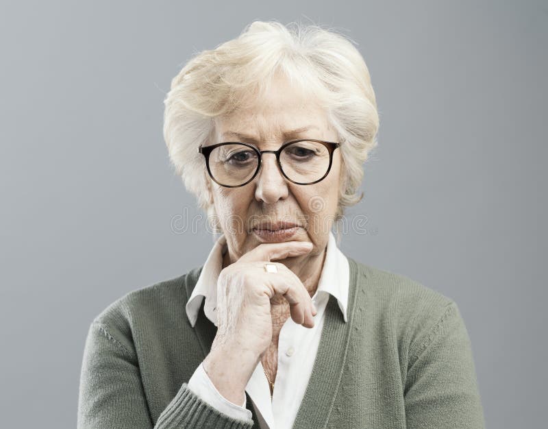 Peinzende hogere vrouw die met hand op kin denken stock afbeeldingen Peinzende hogere vrouw die met hand op kin denken stock afbeeldingen