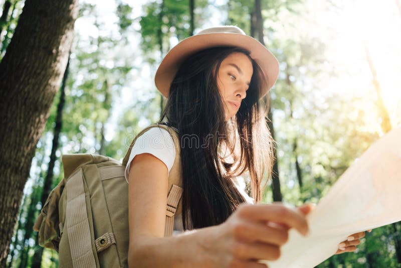 Peinzende moedige vrouw met rugzak die alleen onder bomen in openlucht reizen op Jong reizigersmeisje die in bos en het kijken lo stock foto's Peinzende moedige vrouw met rugzak die alleen onder bomen in openlucht reizen op Jong reizigersmeisje die in bos en het kijken lo stock foto's