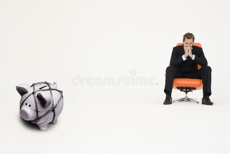 Peinzende zakenman op stoel en piggybank gebonden met kabel die financiële moeilijkheden vertegenwoordigen stock foto's Peinzende zakenman op stoel en piggybank gebonden met kabel die financiële moeilijkheden vertegenwoordigen stock foto's