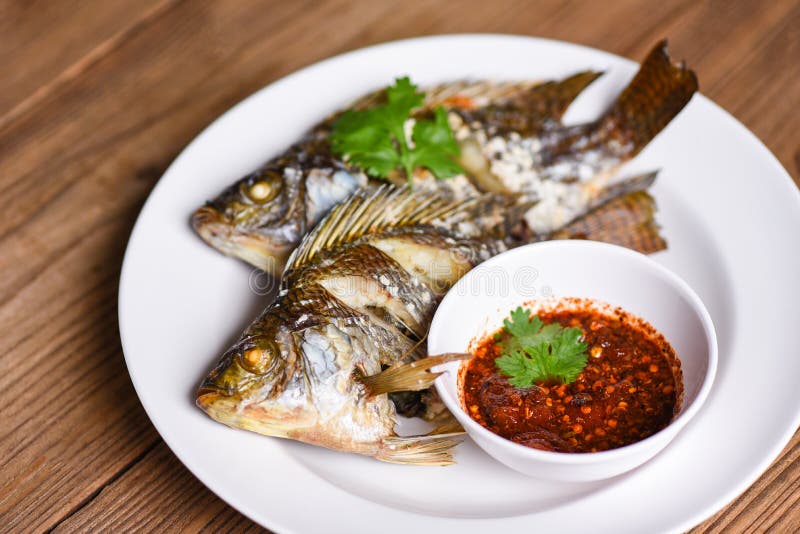 Peixe de água doce da Tilapia com placa branca com molho de chili - peixe de tilápia grelhado com alimentos cozidos