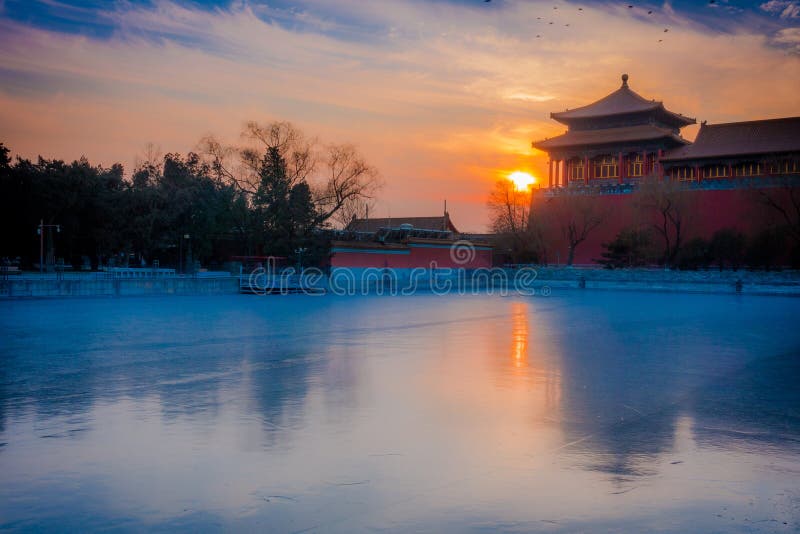 BEIJING, CHINA - 29 JANUARY, 2017: Beautiful temple building inside forbidden city, typical ancient Chinese architecture, frozen lake in front with sunrise in distance, spectacular morning mood. BEIJING, CHINA - 29 JANUARY, 2017: Beautiful temple building inside forbidden city, typical ancient Chinese architecture, frozen lake in front with sunrise in distance, spectacular morning mood.