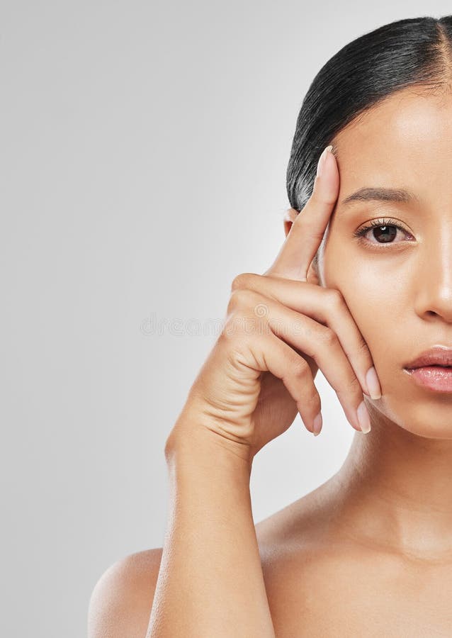 Rosto bonito. mulher jovem e bonita olhando de lado e tocando uma pele  saudável natural sem maquiagem. menina com ombros nus e rosto hidratado  brilhante. conceito de cuidados com a pele