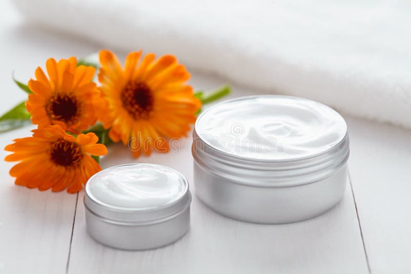 Peli la crema cosmetica struccante con la lozione della stazione termale della vitamina dei fiori della calendula fotografia stock Peli la crema cosmetica struccante con la lozione della stazione termale della vitamina dei fiori della calendula fotografia stock