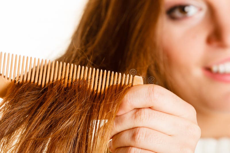Smiling woman combing with brush and pulls at her long hair. Being happy for nice look in daily activity. Smiling woman combing with brush and pulls at her long hair. Being happy for nice look in daily activity.
