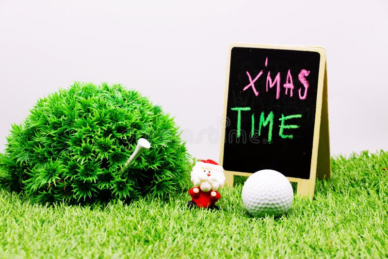 Golf ball with Christmas ornament on green grass , idea for golfer Christmas holiday decoration. Golf ball with Christmas ornament on green grass , idea for golfer Christmas holiday decoration