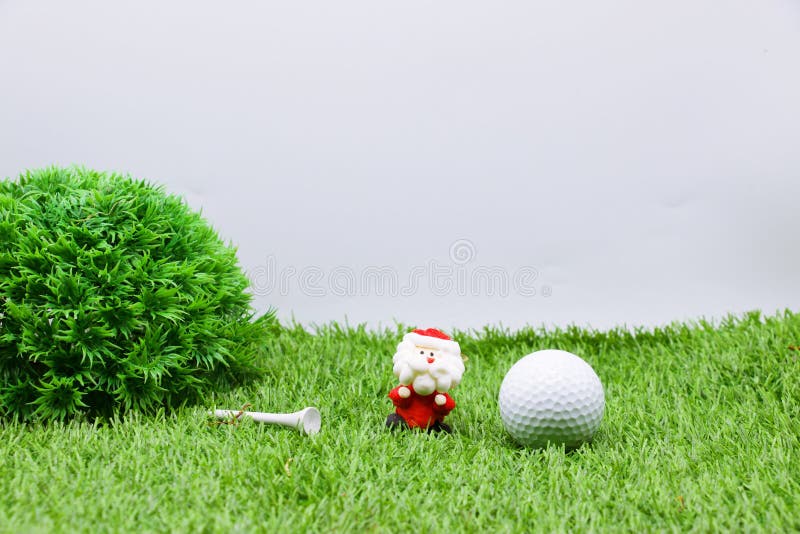 Golf ball with Christmas ornament on green grass , idea for golfer Christmas holiday decoration. Golf ball with Christmas ornament on green grass , idea for golfer Christmas holiday decoration