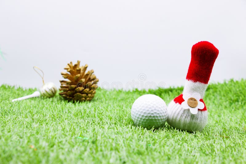 Golf ball with Christmas ornament on green grass , idea for golfer Christmas holiday decoration. Golf ball with Christmas ornament on green grass , idea for golfer Christmas holiday decoration